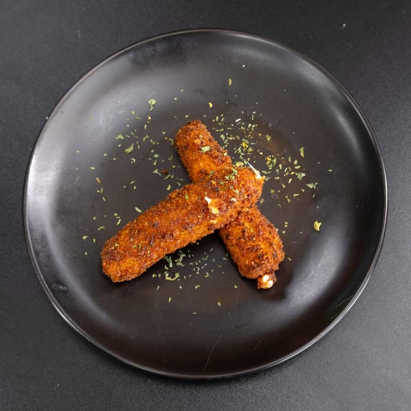 Two golden-brown mozzarella sticks, sprinkled with herbs, on a dark plate.